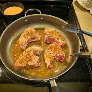 American Guinea hog pork chops sizzling in a skillet