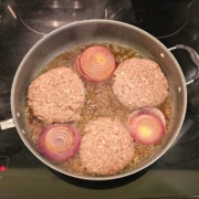 Frying burgers with red onions